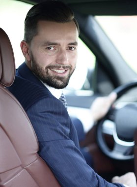 Kameraya bakarak bir arabanın ön koltuğunda otururken yakışıklı genç