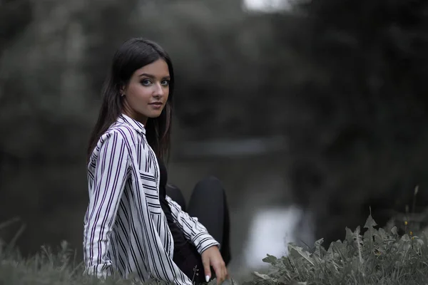 Mujer joven sentada cerca del río — Foto de Stock