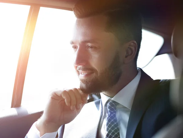 Homme d'affaires souriant assis sur le siège arrière d'une voiture — Photo