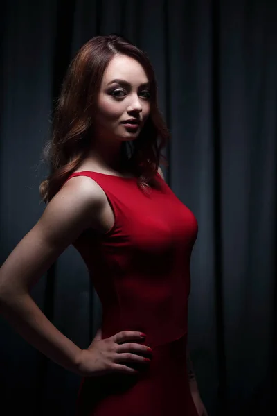 Girl in a red dress on a dark background — Stock Photo, Image