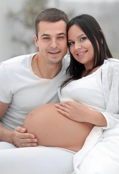 Portrait of pregnant woman with husband sitting on the couch — Stock Photo, Image