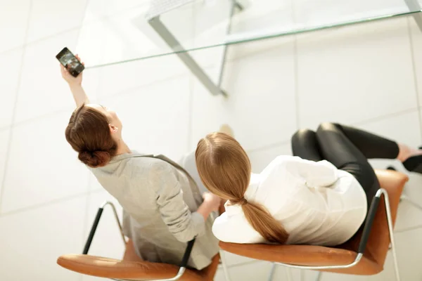 Vista desde la parte superior mujer rear.business mostrando a un colega una foto en su teléfono inteligente . — Foto de Stock