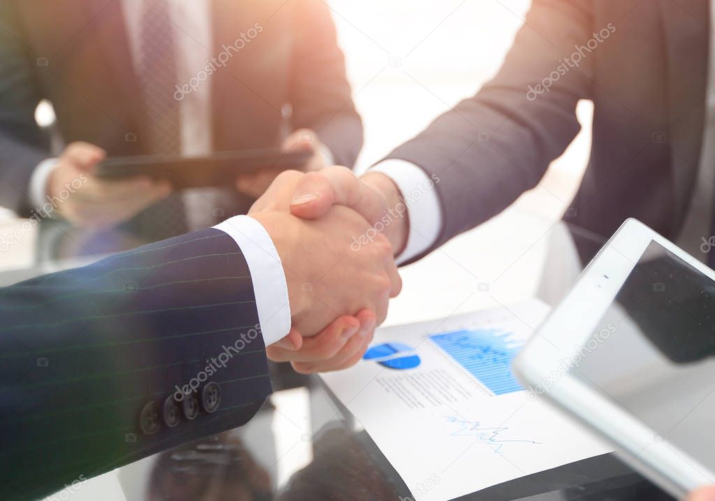 Two businessmen handshaking, congratulating on promotion. Close