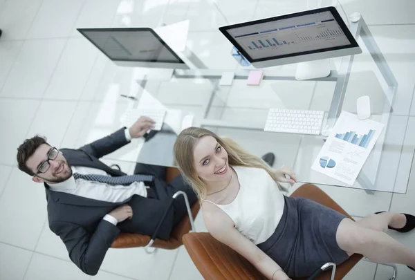 experienced company employees sitting at the desk and looking at the camera.