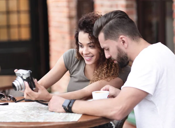 Retrato de um casal sentado em um café e olhando fotos — Fotografia de Stock