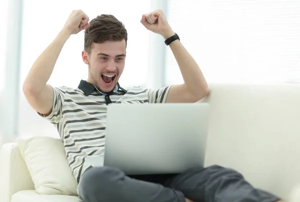 Ευτυχισμένος άνθρωπος με laptop κάθεται στον καναπέ — Φωτογραφία Αρχείου