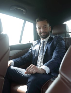 bir arabanın arka koltuğunda oturan işadamı