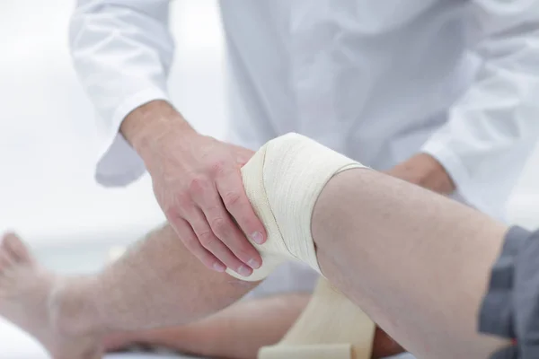 Le médecin soigne la blessure à la jambe du patient dans une salle de clinique — Photo