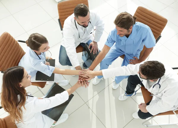 Medisch personeel handen geklemd samen zitten aan een bureau — Stockfoto