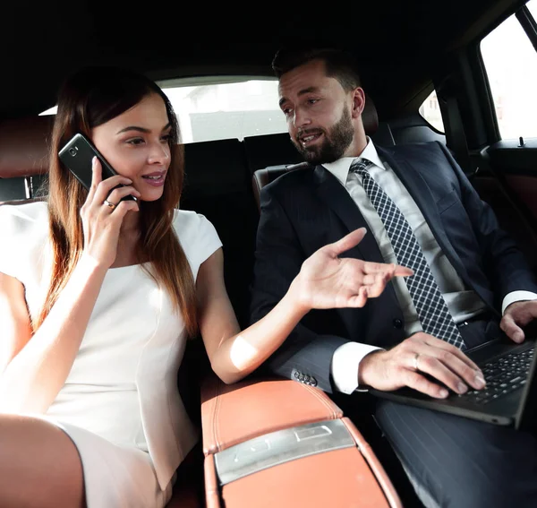 Businesswoman talking on the phone in the back seat of the car — Stock Photo, Image