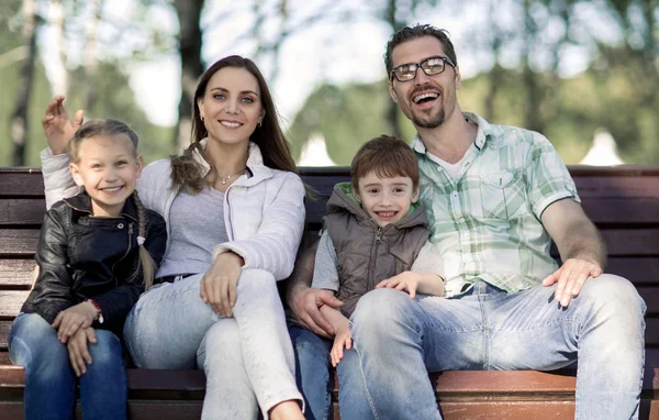 Retrato de uma família feliz sentada em um banco do parque — Fotografia de Stock