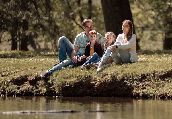 Ouders met kinderen zitten op het gras in de stad Park — Stockfoto