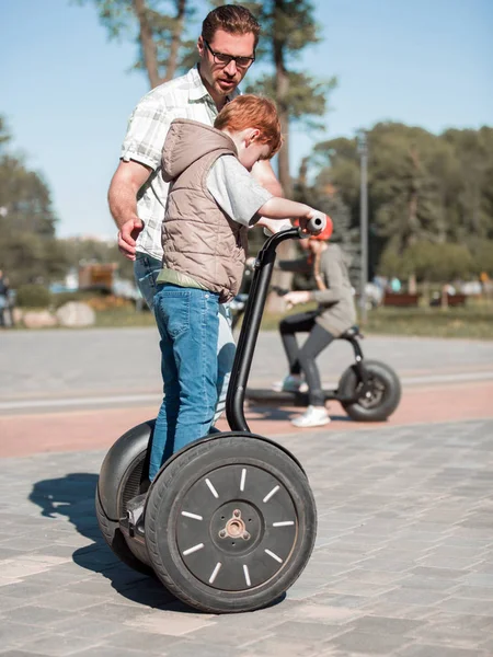 Ο πατέρας διδάσκει ο γιος να οδηγήσω ένα μίνι-hoverboard στο πάρκο — Φωτογραφία Αρχείου