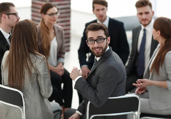Young employee sitting in a circle of colleagues — Stock Photo, Image