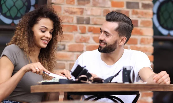 Jeune couple dégustant un café dans un café de rue et riant — Photo