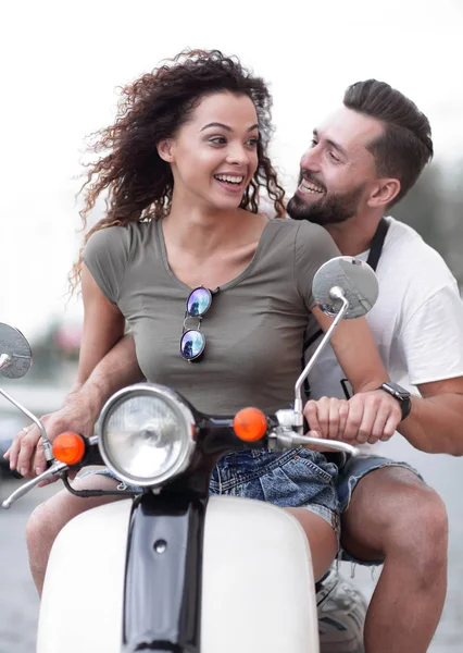 Attractive couple riding a scooter on a sunny day in the city — Stock Photo, Image