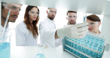 arka plan görüntüsü sıvı cam tüp içinde eğitim microbiologists oluşan bir gruptur.