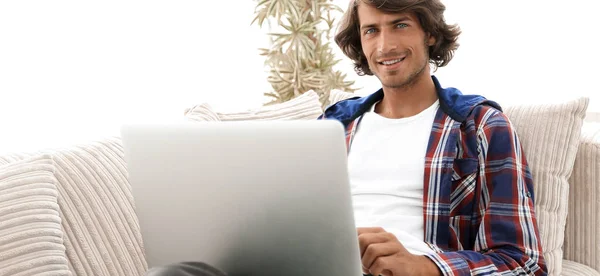 Retrato de um jovem com um laptop sentado em uma cadeira — Fotografia de Stock