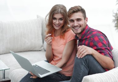 Dizüstü bilgisayarı olan iki öğrenci kanepede oturuyor.