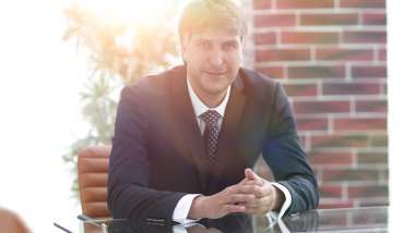 Bir boş konferans salonunda bir masada oturan proje yöneticisi