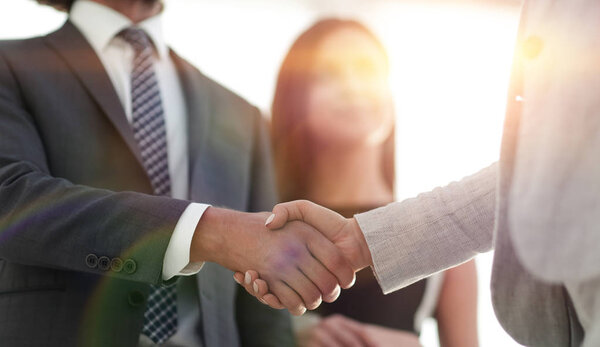 Businesspeople  shaking hands against room with large window loo