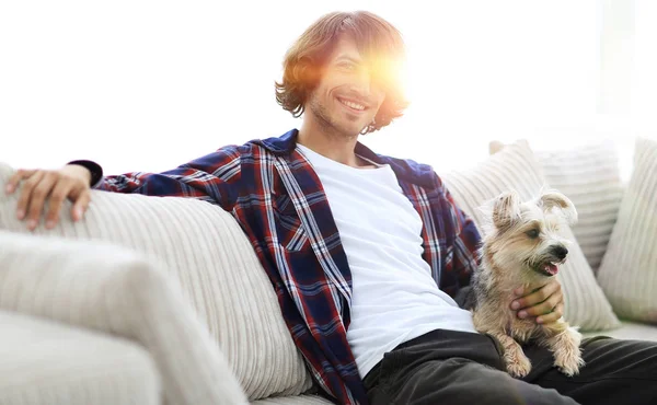 Tipo elegante sentado en el sofá con su perro . — Foto de Stock