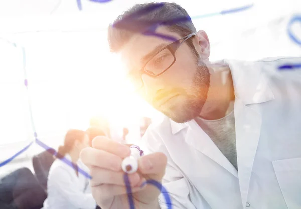 Por detrás de la glass.scientist escribe un marcador en un tablero de vidrio . — Foto de Stock