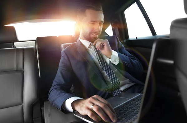 Hombre de negocios lee información sobre el ordenador portátil mientras está sentado en el coche — Foto de Stock