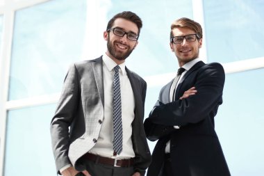 Ofis penceresinin yanında duran iki iş ortağı.