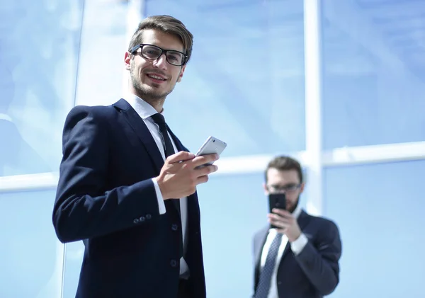 Hombre de negocios moderno con un teléfono inteligente en la oficina de fondo — Foto de Stock