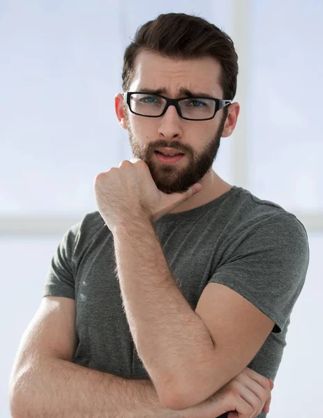 Hombre joven moderno en una camiseta gris sobre un fondo claro — Foto de Stock