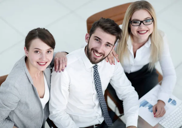 Erfolgreiches Business-Team sitzt am Tisch und blickt in die Kamera. — Stockfoto