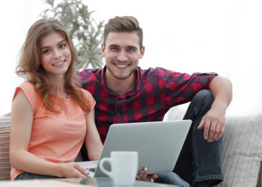 Genç çift çalisarak koltukta oturan laptop