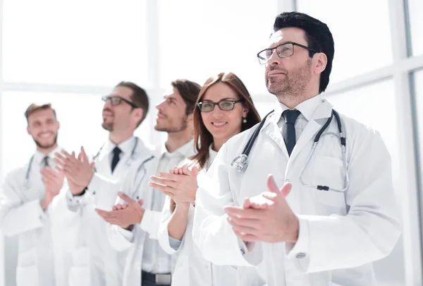 Grupa lekarzy bije brawo, stojąc w szpitalu — Zdjęcie stockowe
