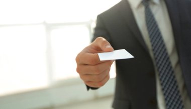 Parlak arka plan üzerinde kartvizit vererek iş adamı