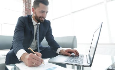 Dizüstü bilgisayarda çalışan ve Notlar not defterinde yapma şık adam