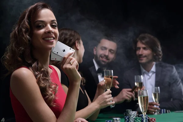 Jovem morena mulher jogar poker no fundo preto — Fotografia de Stock