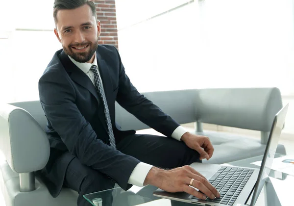 Homem moderno trabalhando no laptop no lobby do escritório . — Fotografia de Stock