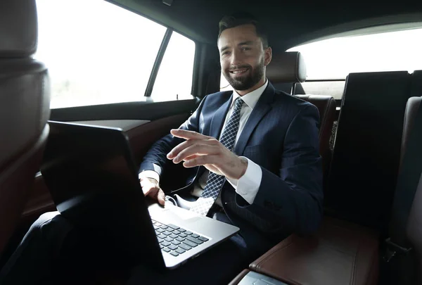 Podnikatel, sedí na zadním sedadle v autě a ukazoval prstem vpřed — Stock fotografie