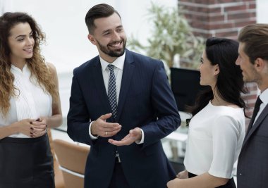 Gülümseyen iş adamları konuşuyor, ofiste duruyorlar.