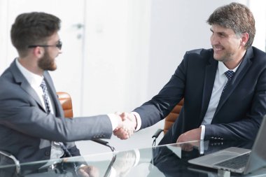 Toplantı sırasında iki iş arkadaşı el sıkışıyor.