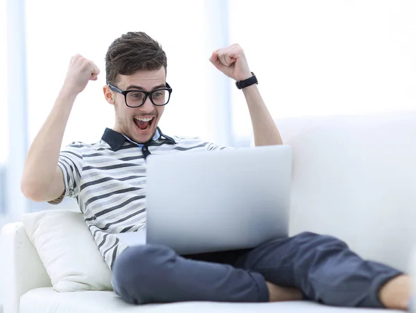 Lycklig man med laptop sitter i soffan — Stockfoto