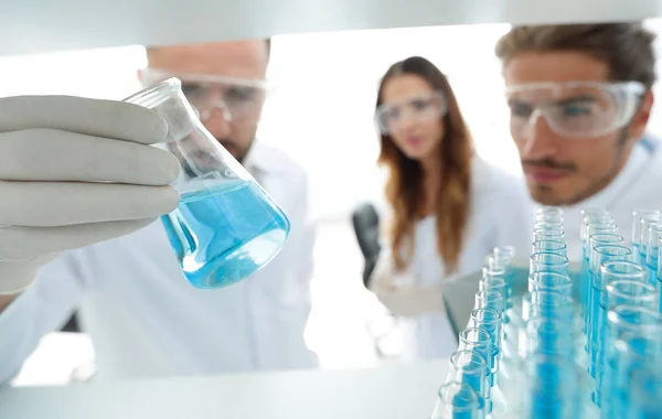 Closeup.a grupp av forskare som studerar vätskan i glasröret — Stockfoto