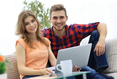 Genç çift çalisarak koltukta oturan laptop