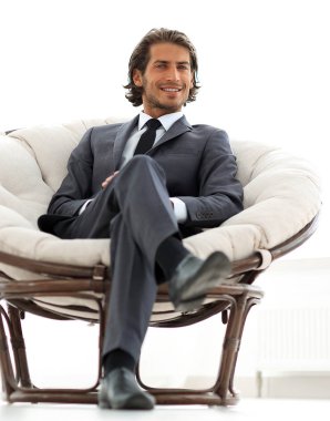 Kendine güvenen işadamı büyük bir rahat sandalyede oturuyor.