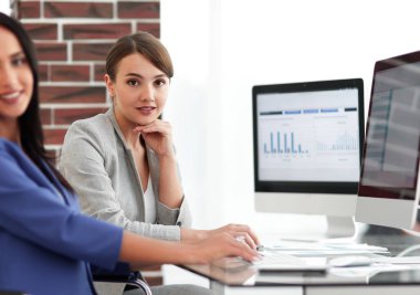 Kameraya bakarak ve oturma işyerinde gülümseyen genç kadın