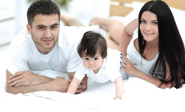 Portret van gelukkige jonge familie samen in bed liggen — Stockfoto