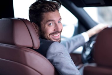 Dikiz aynası, genç adam arabasını sürüyor, kameraya bakıyor.