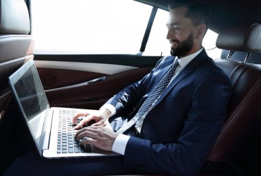 İş adamı arabaya otururken dizüstü bilgisayar ile çalışma