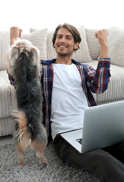 Cara feliz com laptop jubilante na espaçosa sala de estar . — Fotografia de Stock